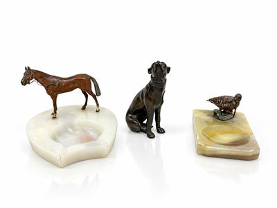 three figurines of dogs and a horse on a white surface