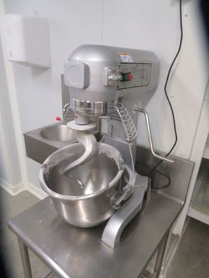 a mixer sitting on a metal table in a kitchen