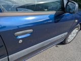 a small blue car parked on the side of the road