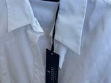 the white shirt is hanging on a rack in the closet