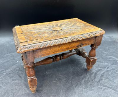 une vieille table en bois avec un plateau sculpté et des pieds tournés