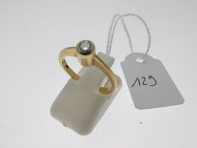 une étiquette blanche et une bague en or posées sur une table blanche