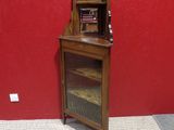 a small wooden cabinet with a glass door in the corner