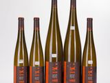 six bottles of wine are lined up on a white surface