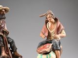 two figurines of a man and a woman sitting on a rock