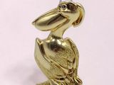gold plated pelican figurine sitting on a pink surface