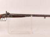 un vieux pistolet au canon en bois, exposé sur un support blanc