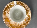 an orange and white cup and saucer on a gray surface