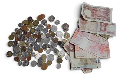 une liasse de billets posée à côté d'un tas de pièces