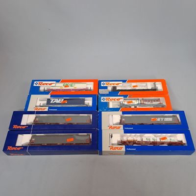trois boîtes contenant des trains miniatures, posées sur une table
