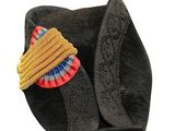 a black hat with a yellow and red brooch on it