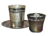 a silver cup and saucer sitting on a saucer