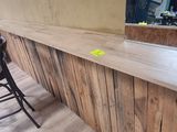a wooden bar with a black chair in front of it