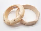 pair of two wooden bangles on a white surface with a tag