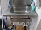 a sink in the corner of a bathroom with a mop on the floor