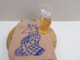 a paper bag with a picture of a giraffe on it next to a glass of beer