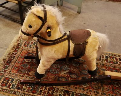 un cheval en peluche posé sur un tapis au sol