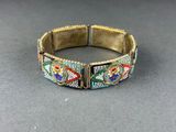 a close up of a bracelet on a table with a gray background
