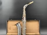 an old saxophone sitting inside of a suitcase on a black surface