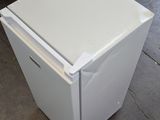 a white refrigerator sitting on the floor in a warehouse