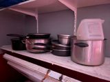 Plusieurs casseroles et poêles sont posées sur une étagère dans une cuisine