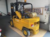 un chariot élévateur jaune avec un fût à l'arrière