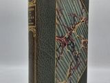 un vieux livre à la couverture verte et aux bordures dorées