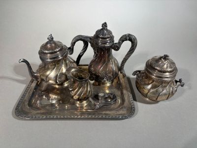 a silver tea set on a tray on a table
