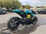 a green motorcycle parked in a parking lot next to other cars