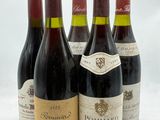 quatre bouteilles de vin sont alignées sur une surface blanche