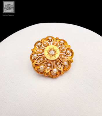 an image of a gold brooch with pearls on top of a white plate