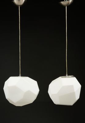 une paire de suspensions en verre blanc et métal sur fond noir