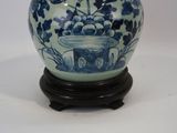 un vase bleu et blanc posé sur un socle, sur une surface blanche