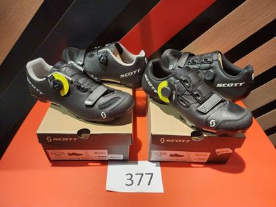Deux paires de chaussures sont posées sur des cartons, sur une table.