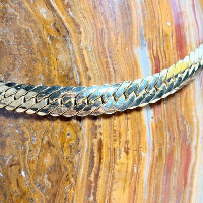 un gros plan d'un collier plaqué or posé sur un rocher