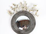 a round mirror with a bunch of flowers on it