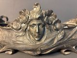 a silver sculpture of a woman with flowers on her head