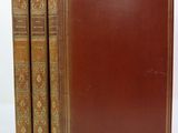 two old books sitting on top of each other on a white surface