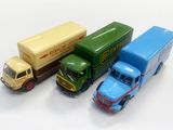 trois camions miniatures posés les uns à côté des autres sur une surface blanche
