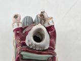 a figurine of a man sitting on a bed with a book