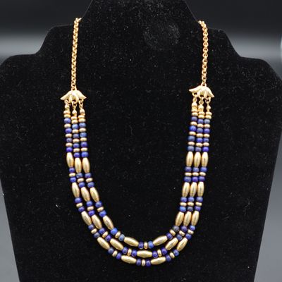 un collier de perles dorées et bleues sur un mannequin d'exposition