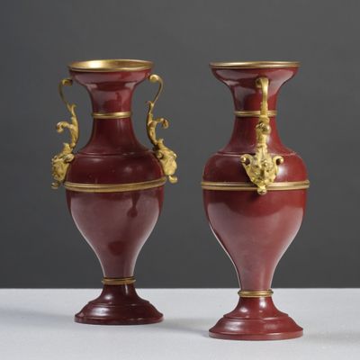 pair of red and gold vases sitting on a white table