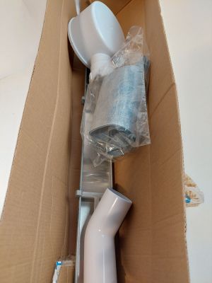une cuvette de WC blanche dans un carton, avec une brosse à l'intérieur