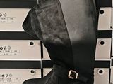 pair of women ' s black boots with buckles in front of a stack of boxes