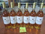 six bouteilles de vin sont alignées sur une table en bois