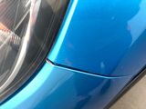 a close up of a car ' s headlight with a blue car in the background