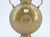 a gold vase that is sitting on a white surface