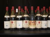 bottles of wine are lined up on a table in front of a black wall
