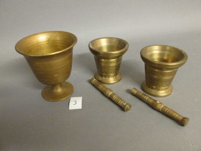 three brass vases and a wooden mallet on a table