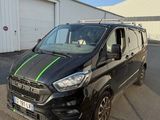 une camionnette noire avec des bandes vertes garée devant un immeuble